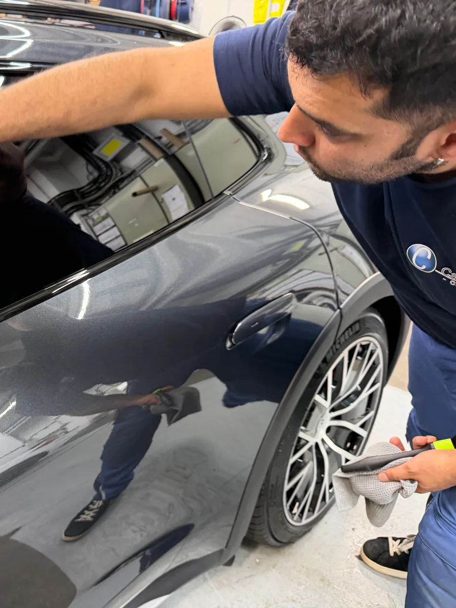 Mitarbeiter prüft bei der Endkontrolle den Lack einer Fahrzeugtür aus nächster Nähe
