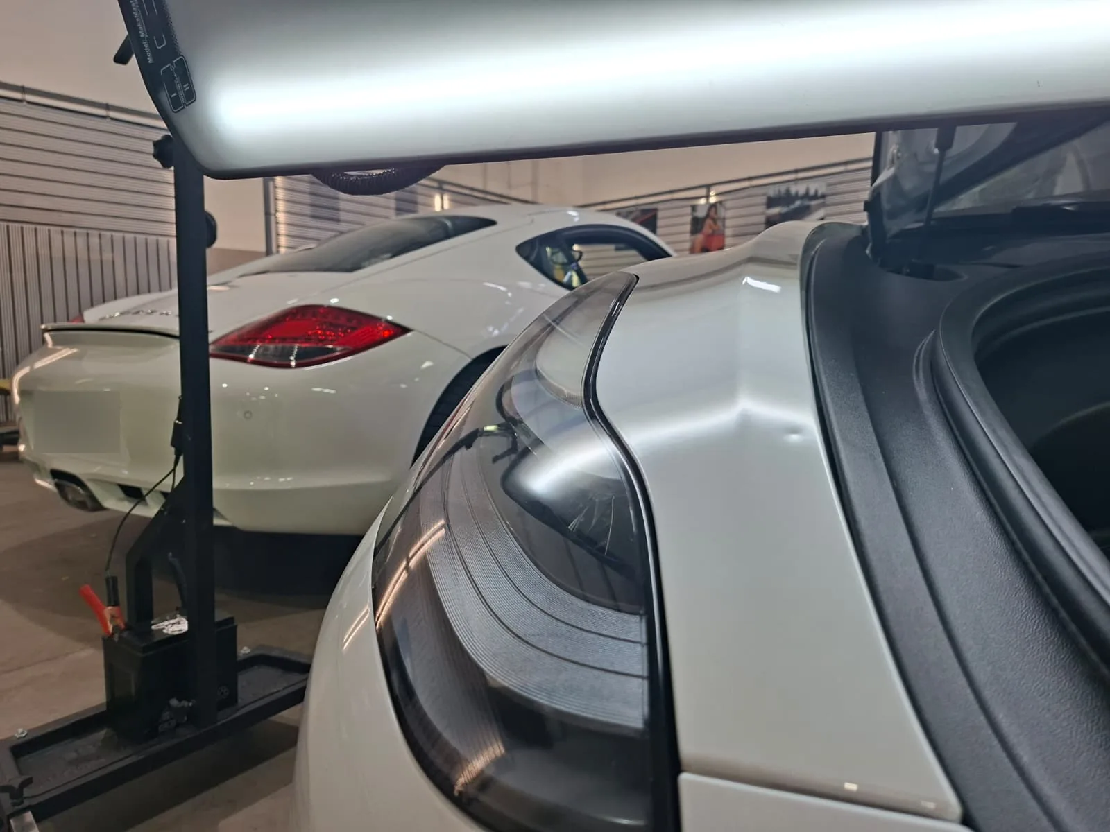 Leuchtschirm über dem Heck eines weißen Porsche macht eine Delle neben der Heckleuchte sichtbar, Dellenentfernung im CarCare Center Leipzig
