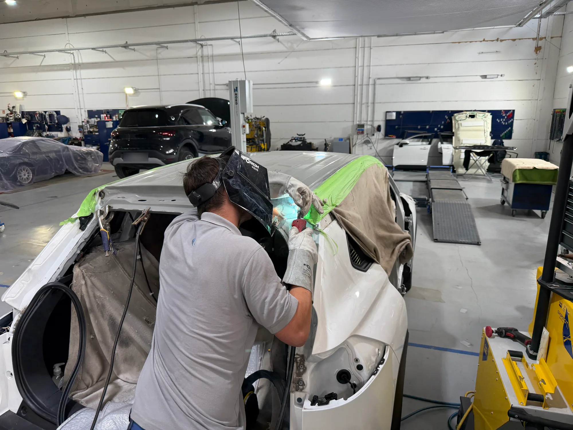 Karosseriebauer schweißt an der Dachsäule eines abgeklebten Unfallfahrzeugs, Unfallinstandsetzung im CarCare Center Leipzig