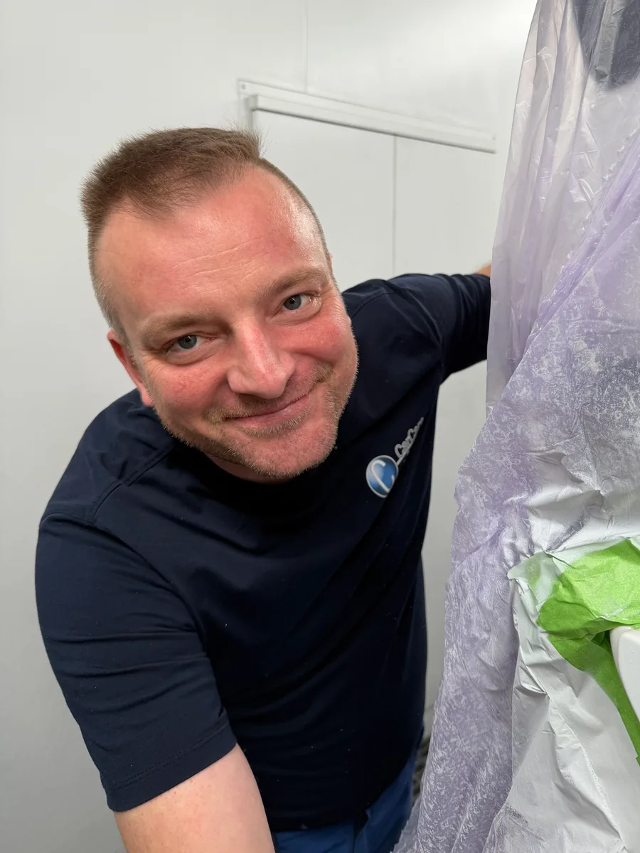 Michal neben einem zum Lackieren abgedeckten Fahrzeug